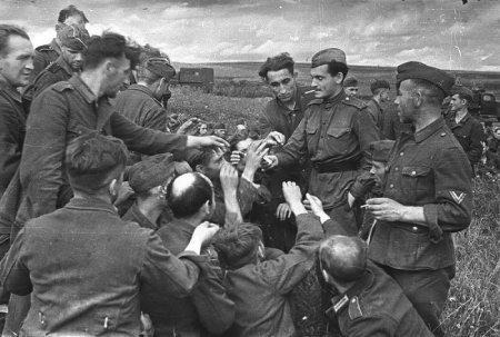 Советский солдат дает сигареты немецким военнопленным, 1943 год.